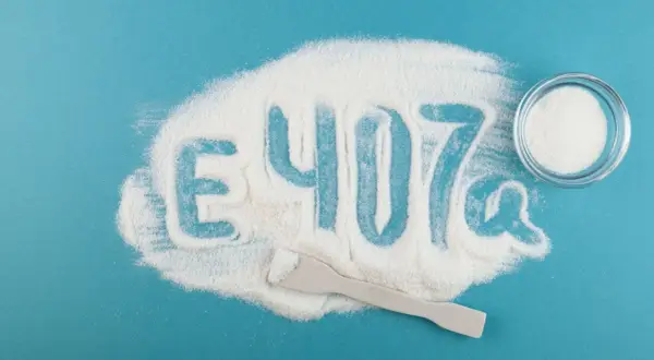 Biały proszek, przypominający cukier puder, tworzy napis "E 407a". To właśnie karagen, dodatek do żywności.